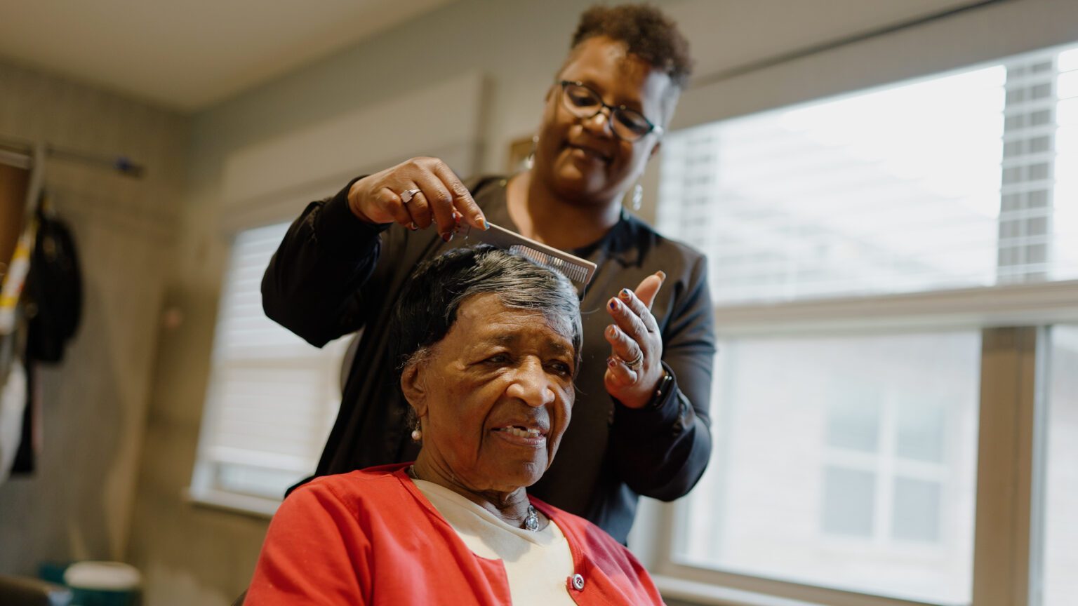 A woman getting her hair styled by a stylist at a skilled nursing facility