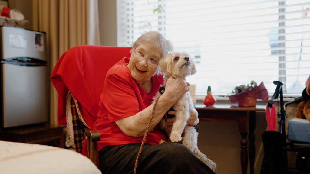 A woman at a skilled nursing facility holding a dog