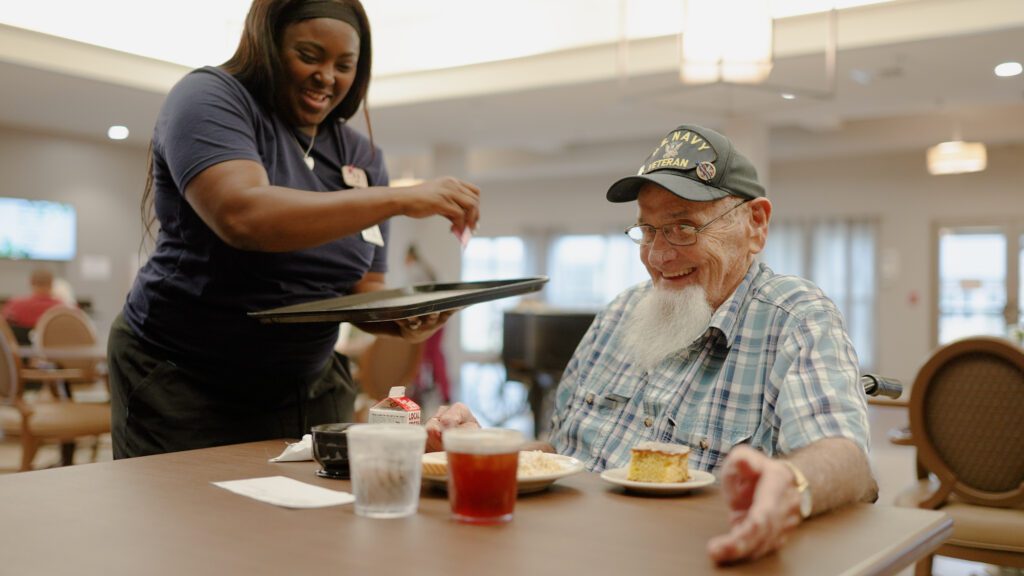 A nurse serves a resident at a skilled nursing care facility dinner